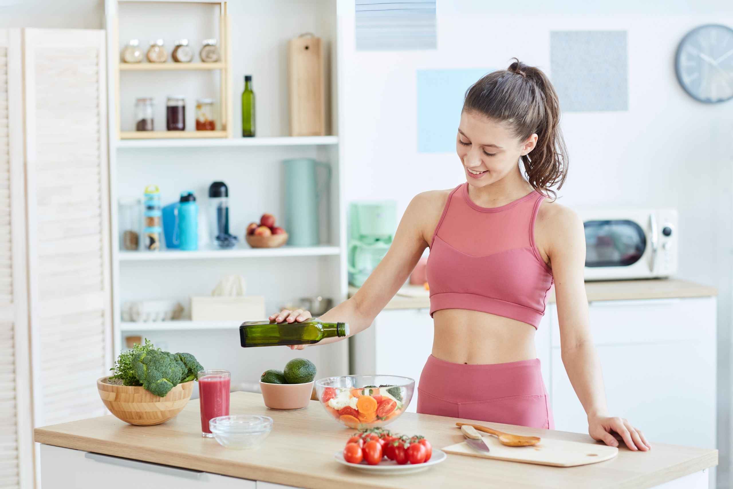 chica vestida de deporte haciendo un almuerzo saludable con aguacate, verduras y fruta