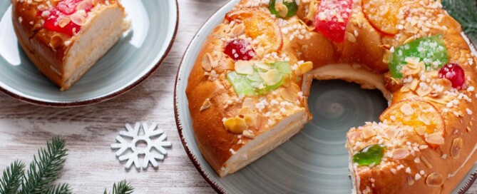 imagen de mesa decorada de navidad con un roscón de reyes que le falta una porción emplatada en otro plato